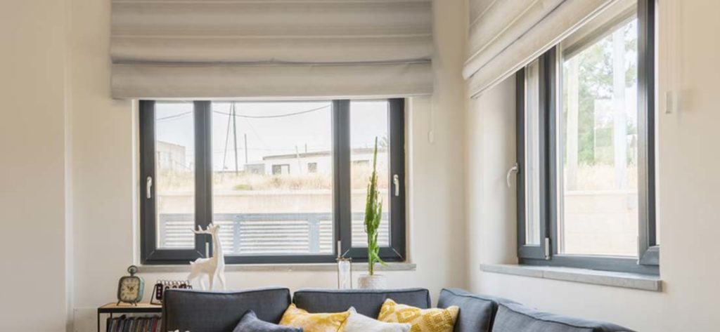 A well-decorated living room featuring elegant Roman shades framing a bright window.