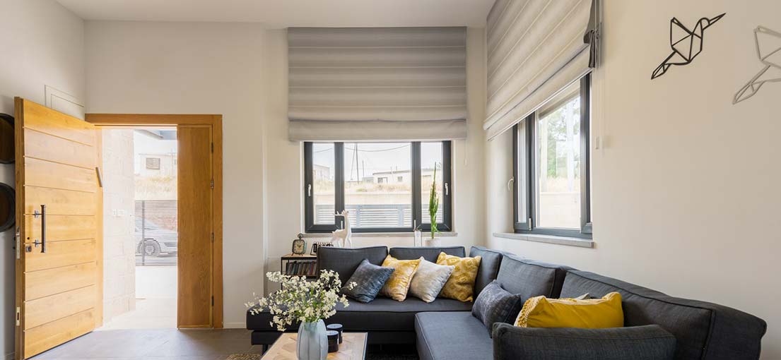 Cozy living room with soft light filtering through Roman shades on the window.