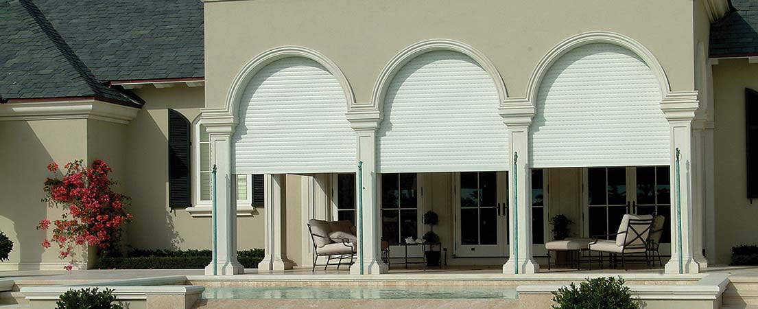 White roll-down blinds on a patio, offering sun protection and a touch of elegance.