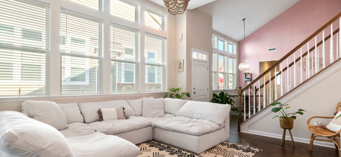 Ground floor living room with custom window treatments, including vinyl and vertical blinds.