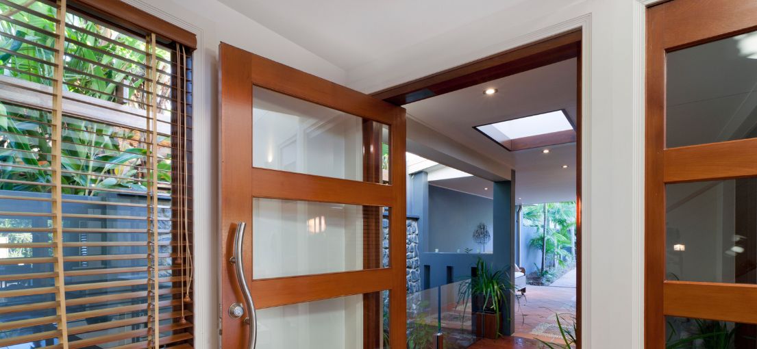 Inviting modern home interior seen through an open wooden door, featuring clean lines and natural light.