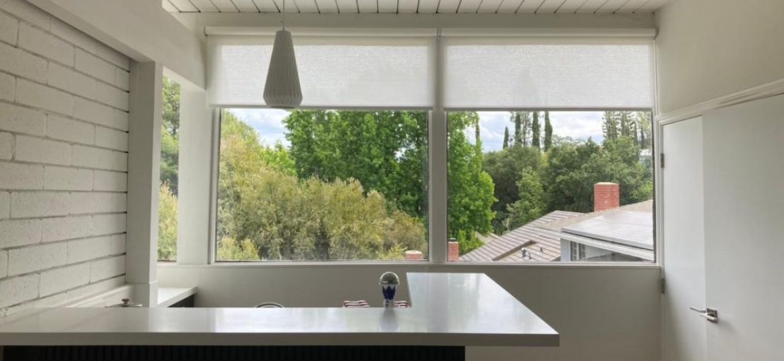 Elegant pull-down window coverings installed by Master Blinds in a chic dining area.