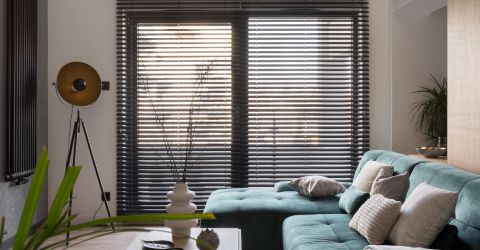 Modern teal sofa accented by newly installed sleek aluminum Venetian blinds from Master Blinds.