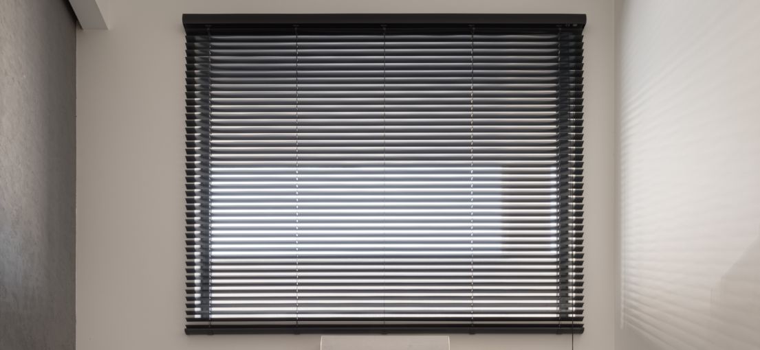 Aluminum blind slats casting soft shadows across a trendy living room, installed by Master Blinds.