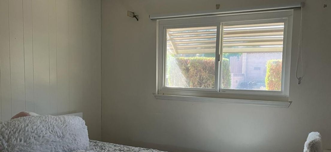 Custom white roller shade providing privacy in a small kids' bedroom by Master Blinds.