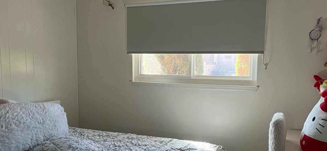 Custom white roller shade providing privacy in a small kids' bedroom by Master Blinds.