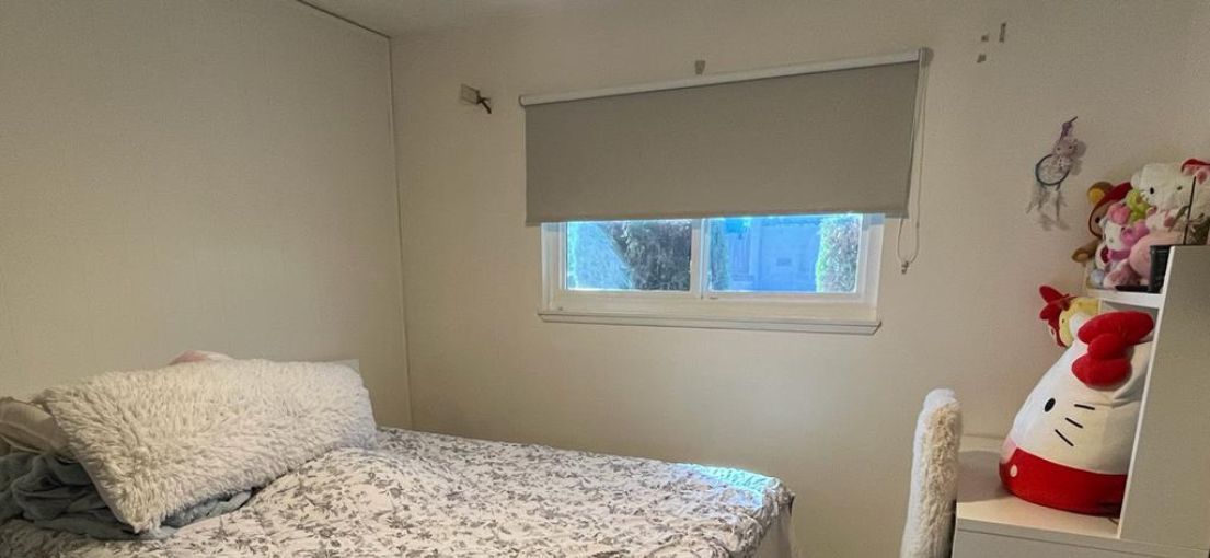 Custom white roller shade providing privacy in a small kids' bedroom by Master Blinds.