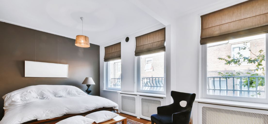 Tailored brown Roman shades casting soft light in a spacious Culver City bedroom.