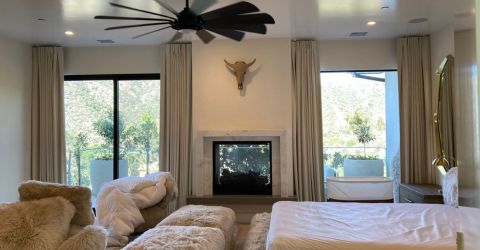 Custom blackout drapes installed in a Hermosa Beach bedroom with soft lighting and plush furniture.