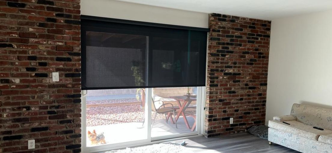 Custom roller shades for a patio door in Calabasas, enhancing the living room’s style with sun protection.