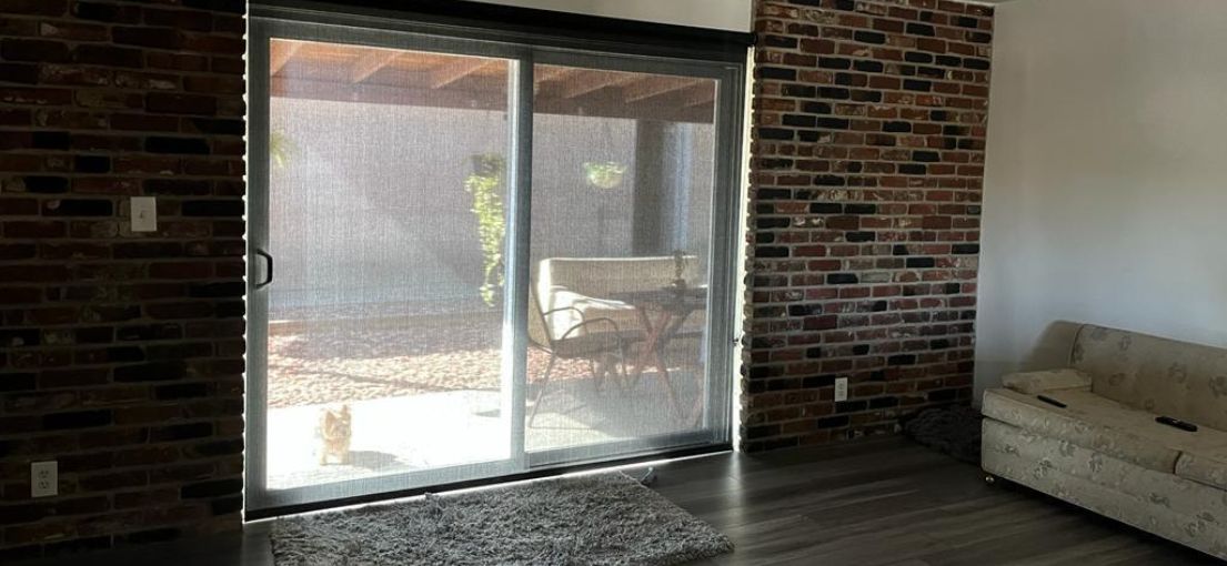 Custom screen roller shades installed on a large patio door in Calabasas living room.