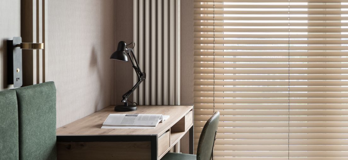 A beautifully designed bedroom in Tarzana with natural light filtering through room darkening vinyl blinds, demonstrating their light-blocking capabilities.