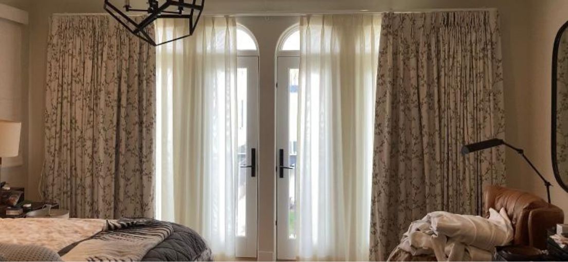 Sophisticated window coverings with custom curtains and Roman shades installed in a Venice bedroom.