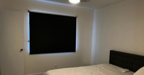 Black pull-down window shade installed in a bright West Hills bedroom.