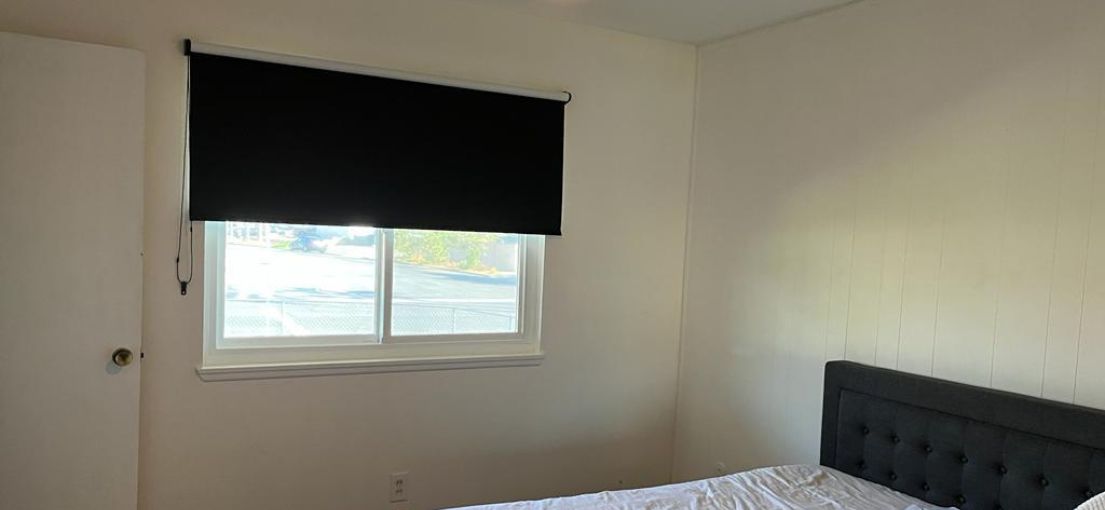 Sleek black roller shades enhancing the contemporary look of a West Hills master bedroom.