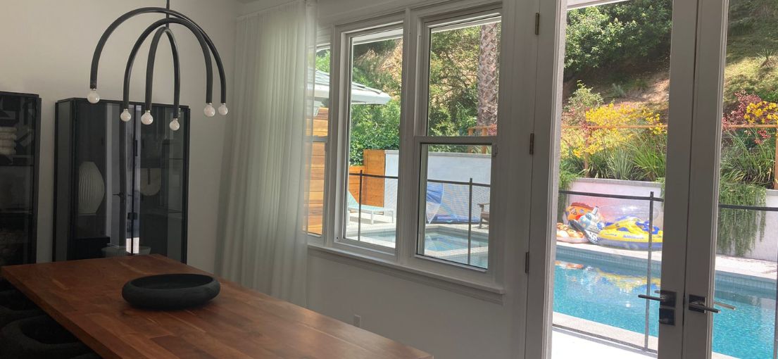 Contemporary dining room with sleek sheer curtains covering large windows, enhancing the space with natural light.