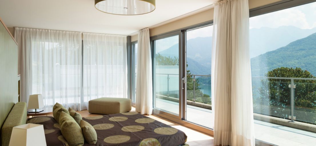 Sunland luxury bedroom with large glass doors and custom curtains framing the scenic view.