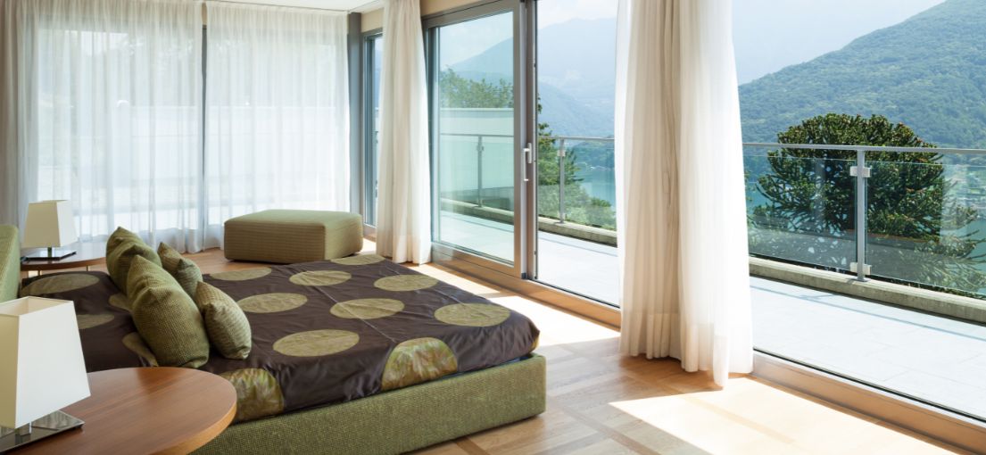 Sunland luxury bedroom with large glass doors and custom curtains framing the scenic view.