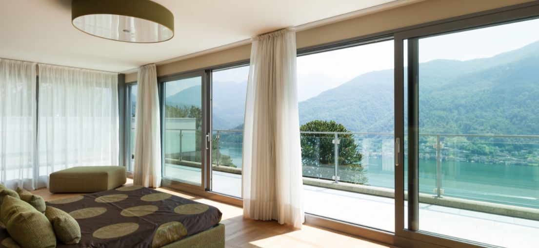 Bright and airy Sunland bedroom with custom light drapery complementing the large windows.