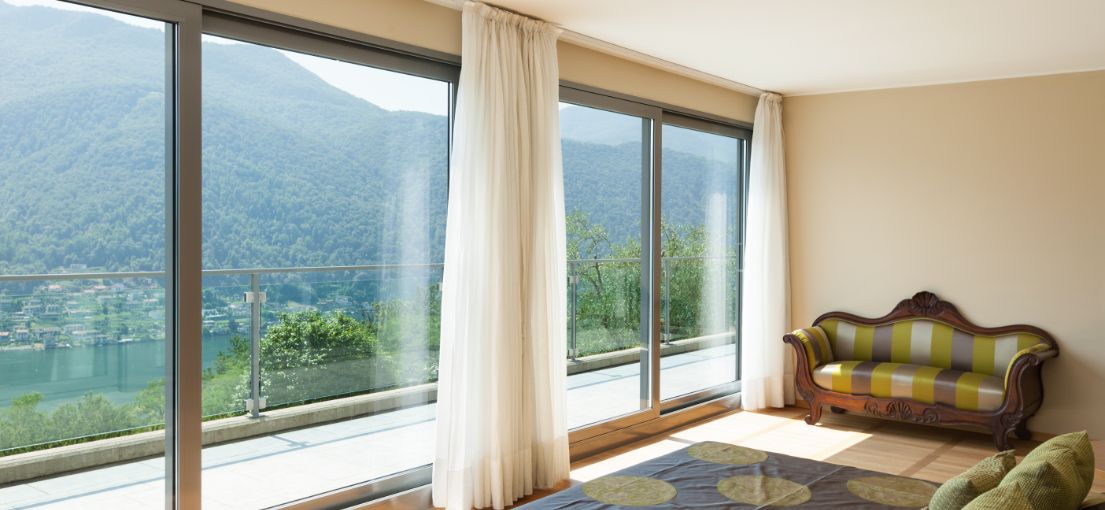 Bright and airy Sunland bedroom with custom light drapery complementing the large windows.