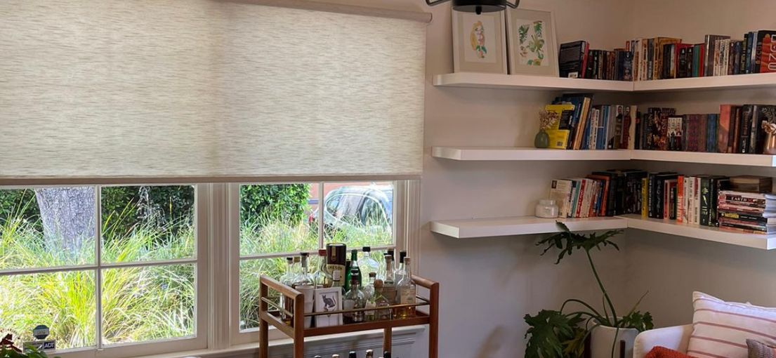 Living room windows with sheer roller shades partially pulled up in Sunland residence.