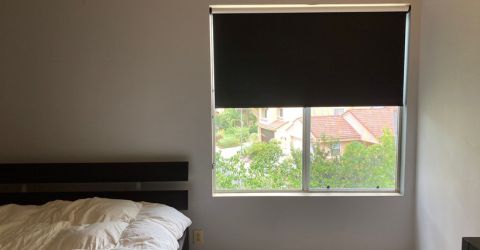 Custom black blackout shades providing full sun protection in a Brentwood bedroom.