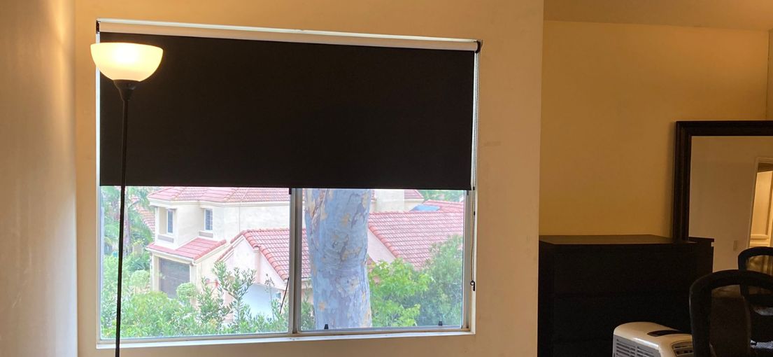 Black blackout roller shades installed in a Brentwood bedroom window.