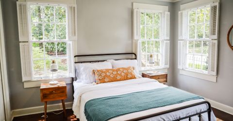 Traditional bedroom in Porter Ranch featuring white plantation shutters on large windows for enhanced light control.