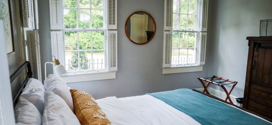 Elegant Porter Ranch bedroom with classic white shutters on windows, partially opened for natural light.