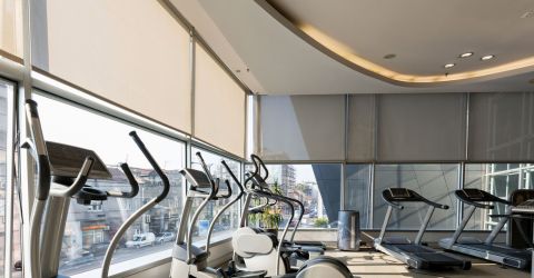 Spacious modern gym in a commercial building with motorized window shades for light control.